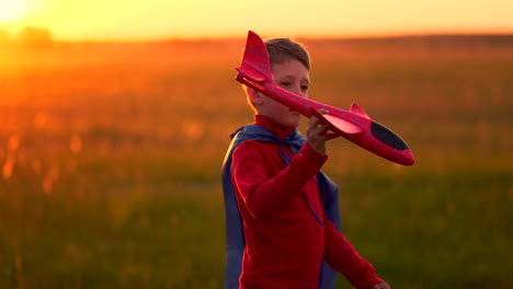 A-happy-boy-with-a-raincoat-imagines-himself-an-airplane-pilot-and-runs-with-a-toy-across-the-field-thinking-that-he-is-an-airplane-pilot-at-sunset.